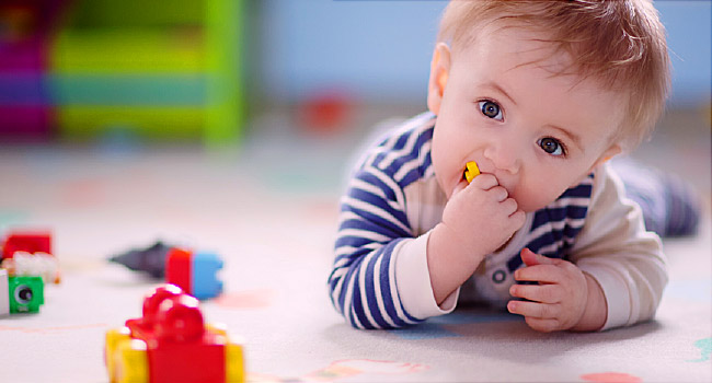 bebê de 8 meses deitado no chão brincando. texto em destaque: Sinais de Autismo: Como identificá-los em bebês a partir de 8 meses!